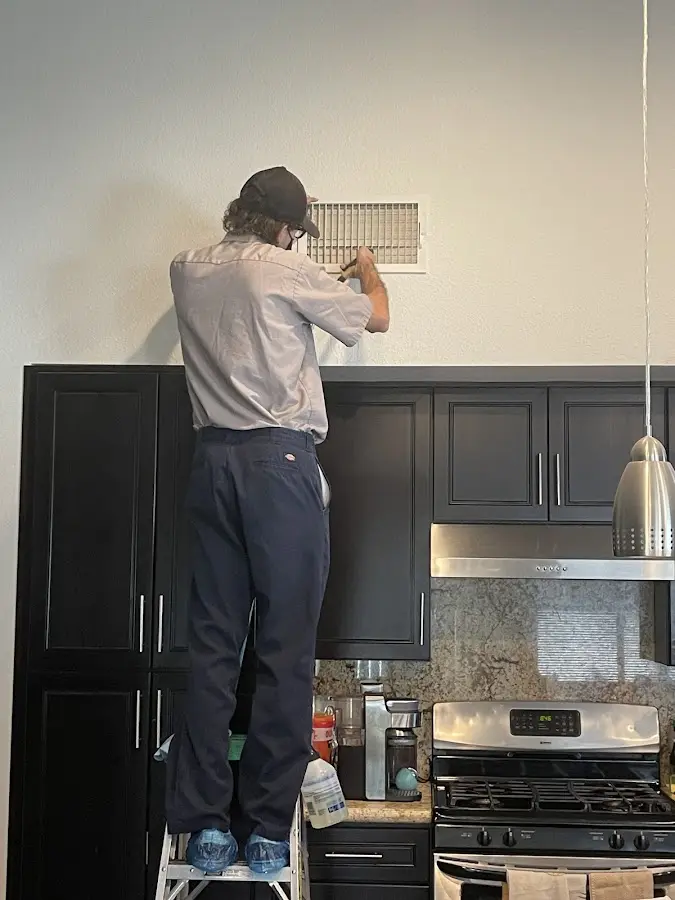 Technician inspecting an air vent during HVAC service in Alvarado